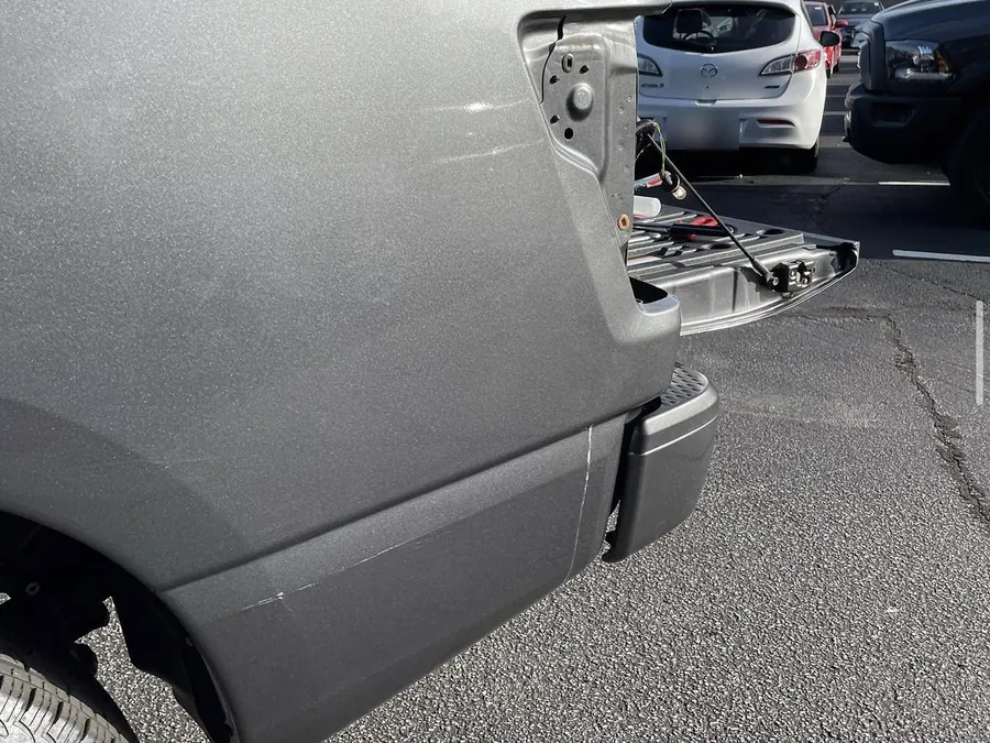 The bedside of a grey pickup in a parking lot, the tailgate down with tools on it